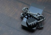 Smartphone envolto por uma corrente e um cadeado, simbolizando o bloqueio e a restrição de acesso a plataformas digitais.