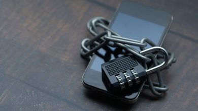Smartphone envolto por uma corrente e um cadeado, simbolizando o bloqueio e a restrição de acesso a plataformas digitais.