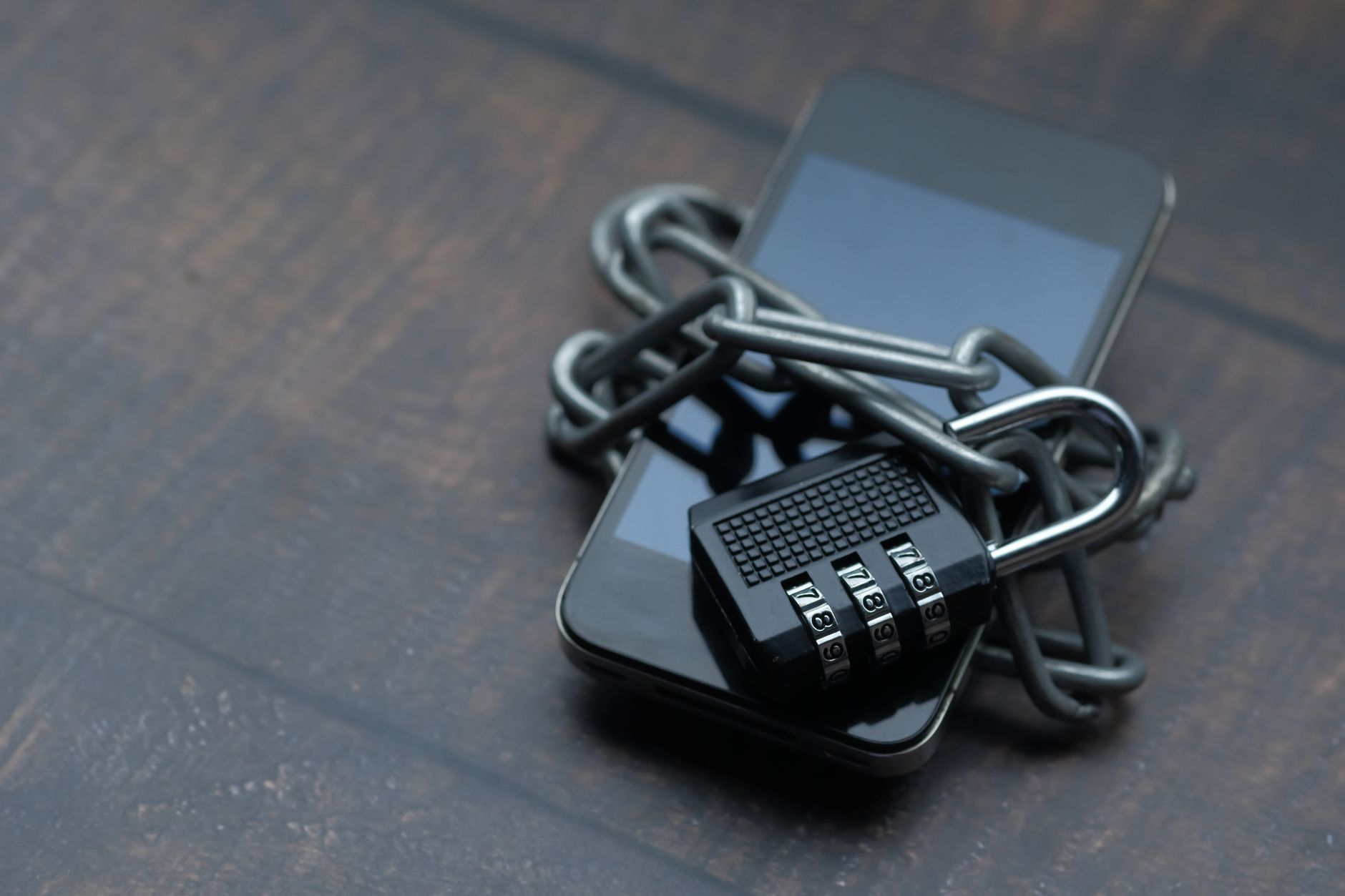Smartphone envolto por uma corrente e um cadeado, simbolizando o bloqueio e a restrição de acesso a plataformas digitais.