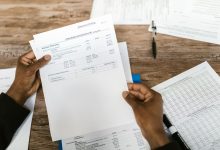 Mãos segurando documentos financeiros para análise e preparação tributária.