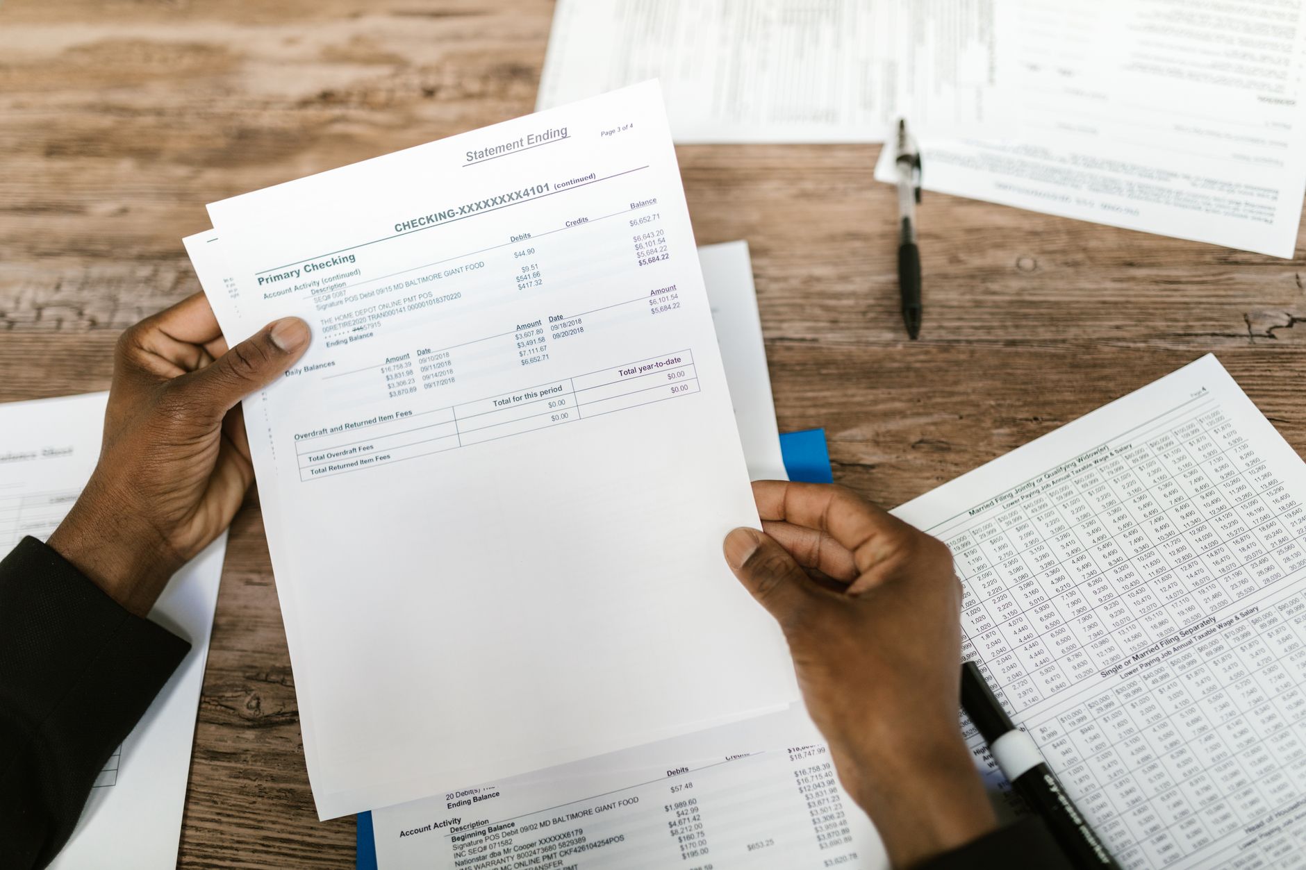 Mãos segurando documentos financeiros para análise e preparação tributária.