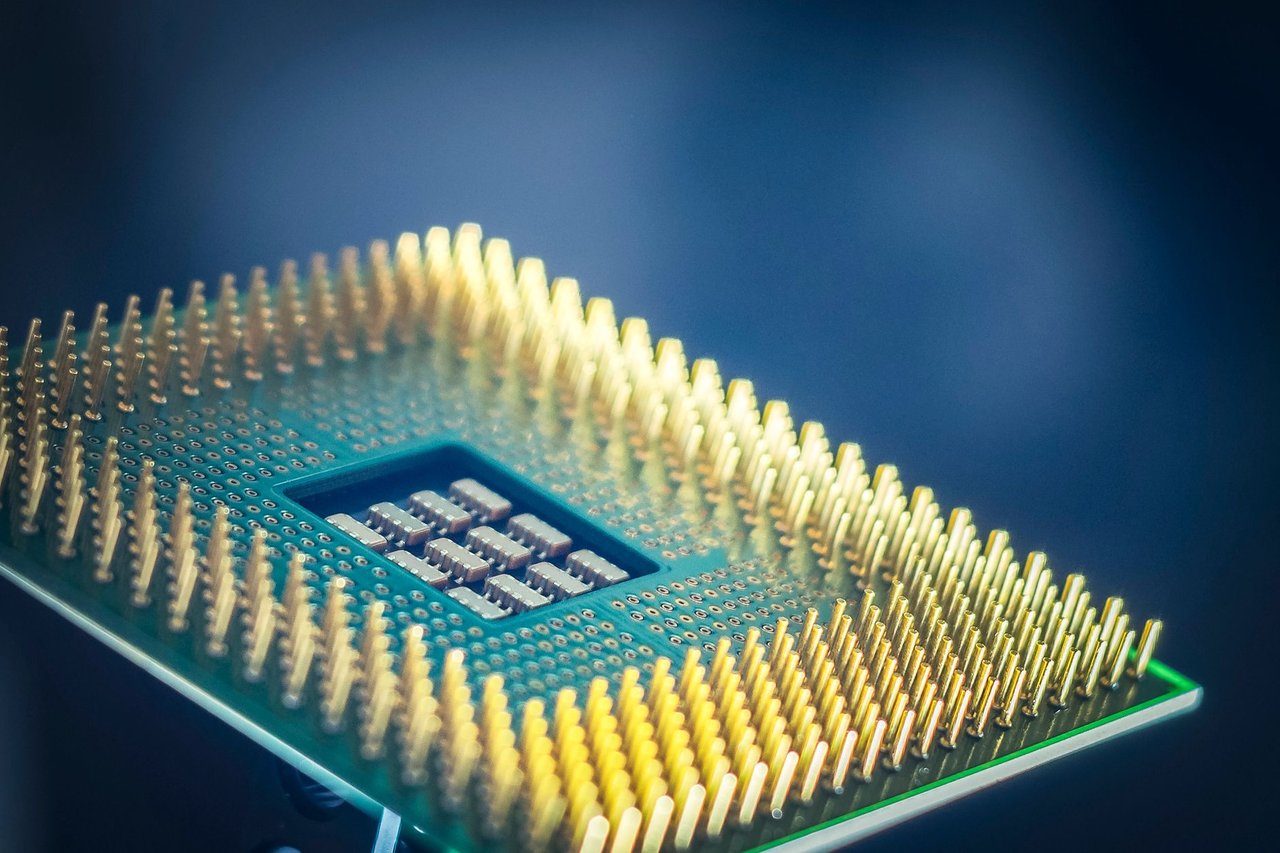 Imagem aproximada de um chip de computador com contatos dourados sobre fundo azul.