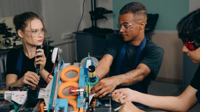 Três engenheiros colaboram diante de equipamentos industriais em uma fábrica moderna.